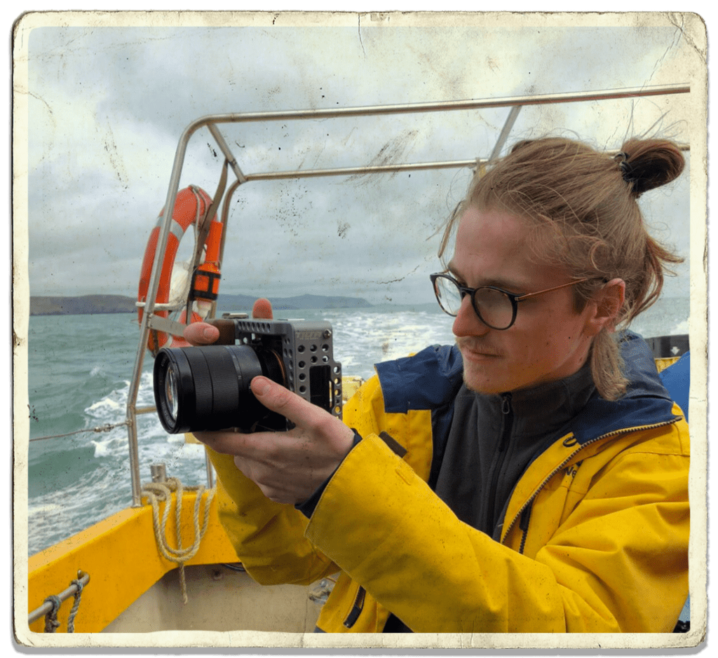 Sam Oliver is filming using a camera on a boat.