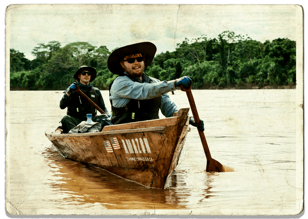 Two adventurers paddling down the Amazon in a dugout canoe during the Amazon Canoe Challenge 2019.